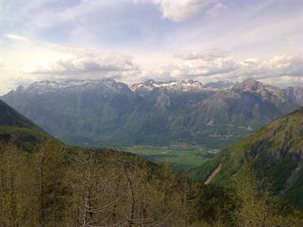 In lontananza le Alpi Giulie italiane e slovene sembrano abbracciarsi sopra l'abitato di Bovec.