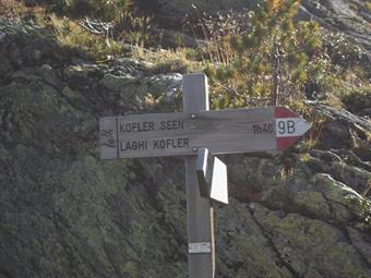 Nei pressi della baita chiusa alla fruizione escursionistica un cartello c'informa sulla prosecuzione del sentiero verso i lontani Kofler Seen/Laghi del Covolo.