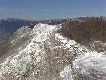 Il sentiero segnalato prosegue lungo la rocciosa cresta innevata della Podrta Gora nad Ajdovščino (827), tralasciando lungo il cammino una diramazione diretta ad una cappelletta ed al lontano fondovalle.