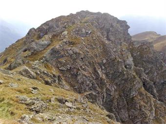 La dorsale prosegue quindi verso la quota 2416 della Cima Mezzana, raggiungibile su tracce, transitando in una zona rocciosa con ulteriori ruderi risalenti alla Grande Guerra.