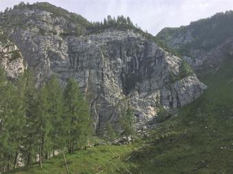 Rientrando nel magro pasolo, il sentiero conduce ad un'ampia conca alpina, racchiusa da imponenti bancate rocciose.