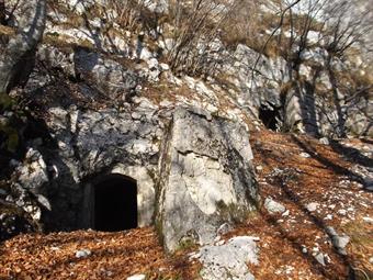 Lasciata la postazione proseguiamo in salita sopra di essa a oriente su una buona traccia fino a raggiungere alcuni ingressi scudati con muri angolati di un paio di caverne.