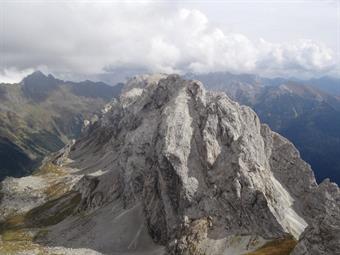 Nel frattempo il passo si popola d’ogni tipo di fauna: dai mocassinati agli imbragati. Partono i canti, le chiacchiere ad alta voce o i continui test di prestanza in gare di eco e yodel. Trovandomi accerchiato e pensando ad una tappa prima di raggiungere 