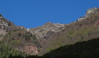 Al secondo curvone un cartello fa ripiegare a destra in direzione di Termine di Cadore. Poco dopo la strada vira a sinistra verso una  baita dal tetto rosso. Non bisogna seguire l'invitante discesa verso il casolare ma infilarsi, continuando diritti, in u