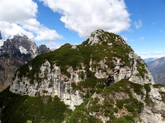 Giungendo in casera spunta anche il monte Serva. La giornata è splendida, calda e ventosa. L'aiaron gonfia le nubi e le porta a spasso per gli azzurri. Preferisco questi cieli a quelli monocromatici, luci ed ombre crean ricami e figure sulle fiancate dei 