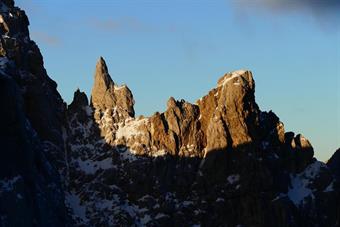 Fino a che, dopo un paio di minuti, Eolo riprende fiato. E parto come una fusetta a cercare un riparo ove la cresta s’allarga. Giungo a pochi metri dalla cima. Cinque minuti appena. Mi si presentano delle rocce, pulite, con un cavo di sicurezza. Mi domand