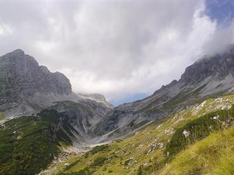 In lontananza verso ponente appare l'inconfondibile intaglio della Sella Prevala, racchiusa dai contrafforti rocciosi del Veliki Stador, Golovec e Leupa.