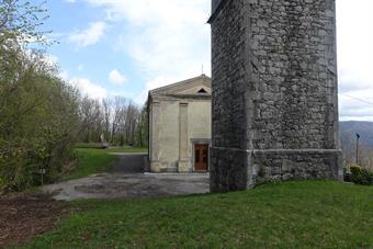 La Chiesa di Sant'Andrea, con il campanile e il retrostante monumento ai caduti. Sulla sinistra si intravedono i cartelli che segnalano il sentiero di discesa